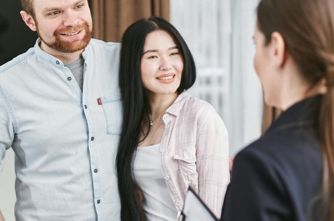 Smiling interracial couple engaging with a professional advisor in an indoor setting.