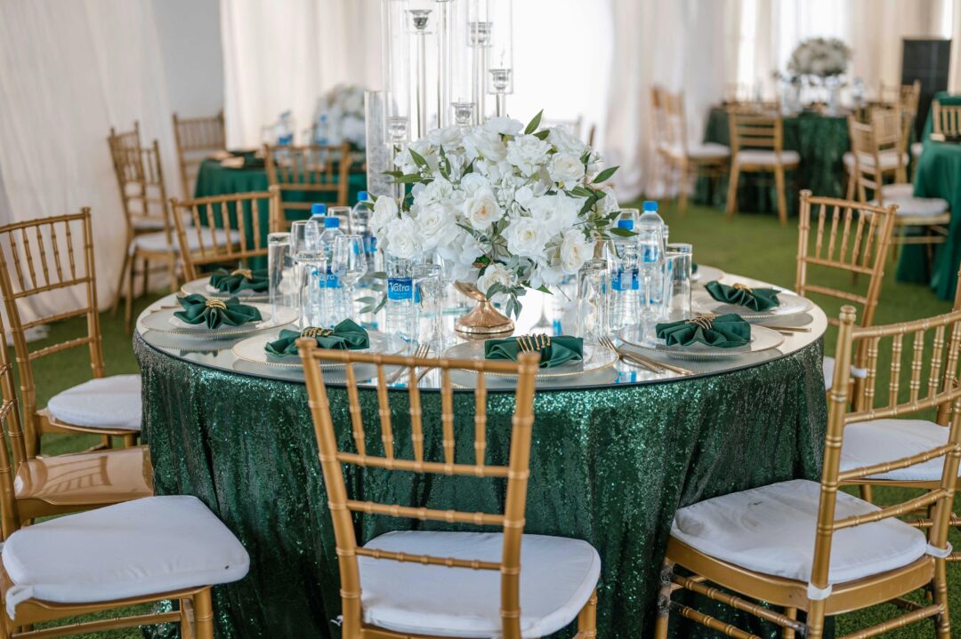 Emerald and gold wedding reception with lush greenery garlands, gold candlesticks, ivory florals, and emerald velvet table runners in an elegant ballr