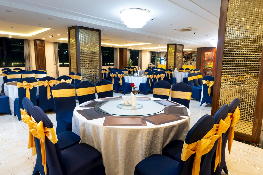 Navy and gold wedding reception with tall floral centerpieces, candlelight, navy velvet linens, and gold geometric accents in an elegant ballroom