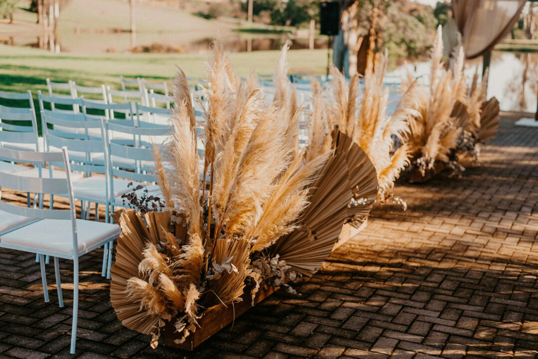 Terracotta wedding tablescape with clay-toned linen, dried pampas grass, orange and rust dahlias, and warm candlelight at a desert boho outdoor recept