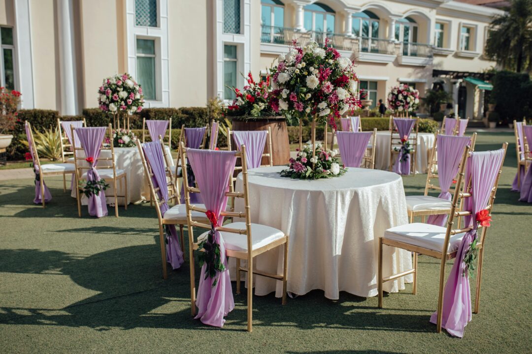 Lavender wedding ceremony in a flower field with purple lavender bundles tied to wooden chairs, soft lilac florals, and a wisteria-draped ceremony arc