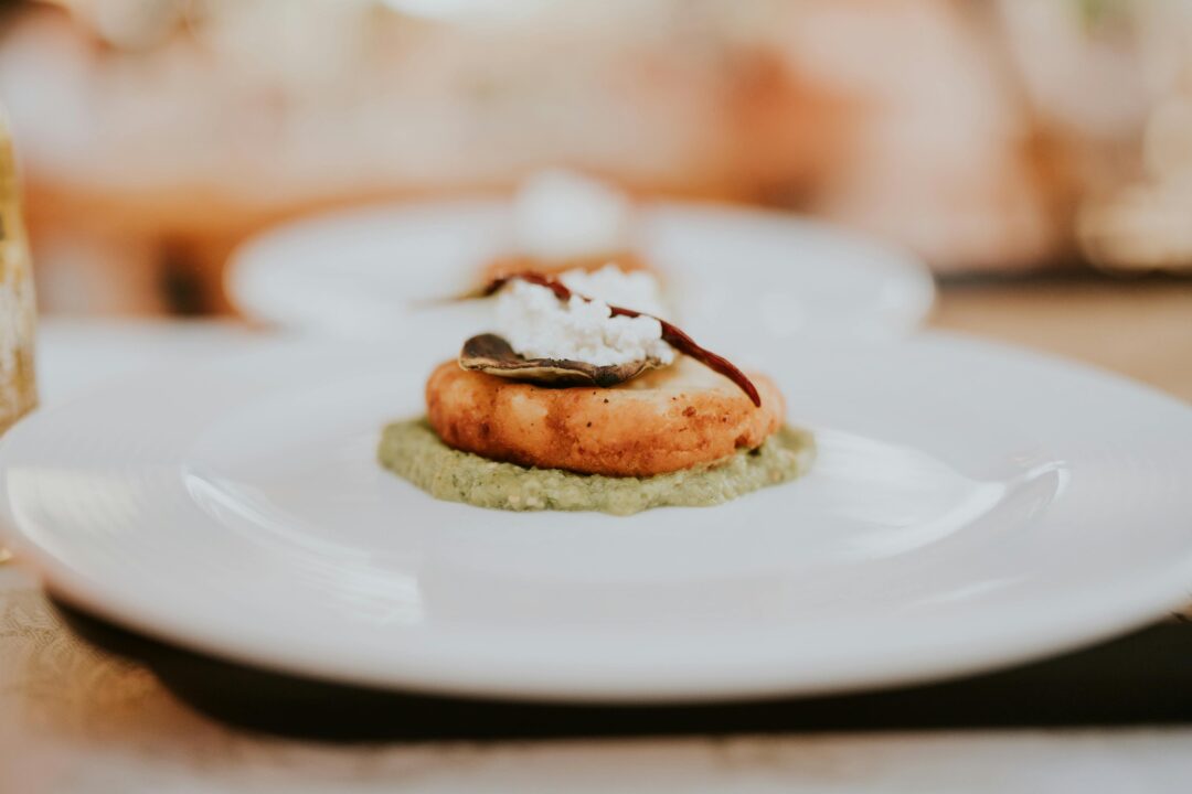 close-up of a beautifully plated wedding appetizer course - scallops or charcuterie on elegant white china at a reception table