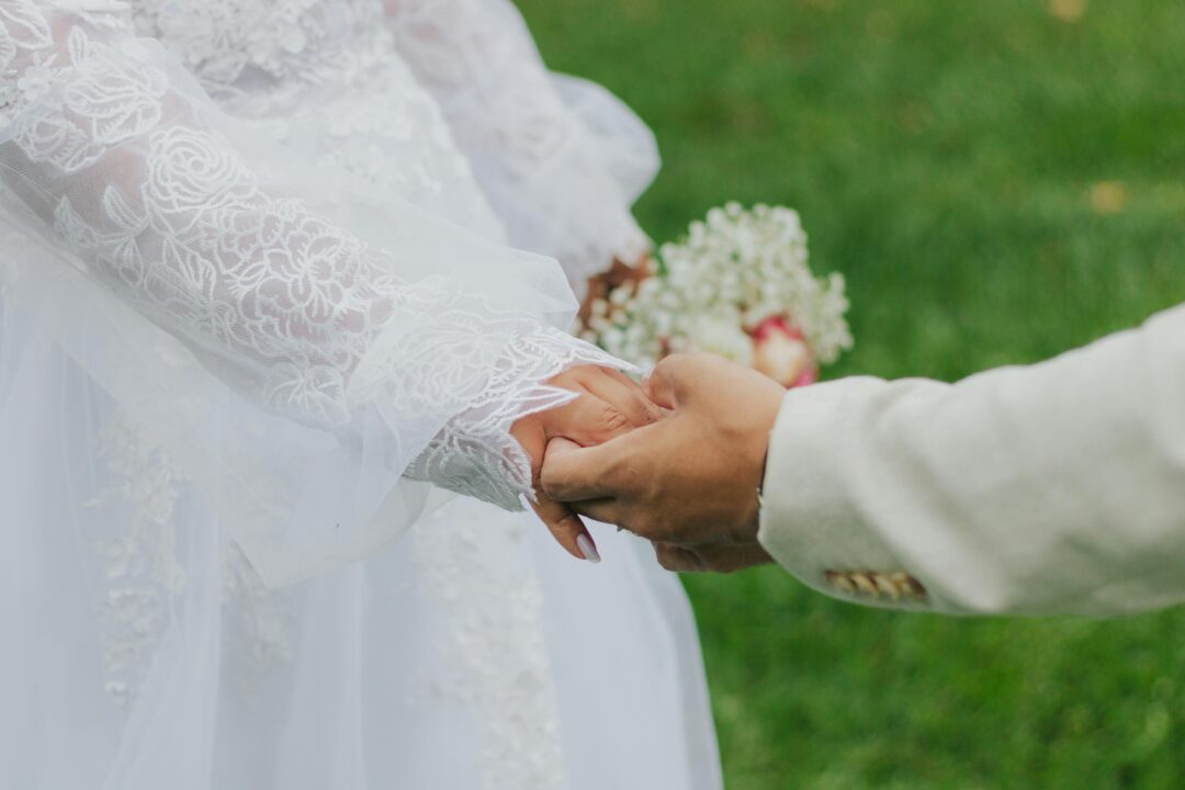 bride holding handwritten vow cards, outdoor ceremony setting, close-up of the cards with lush floral arrangements in soft focus background