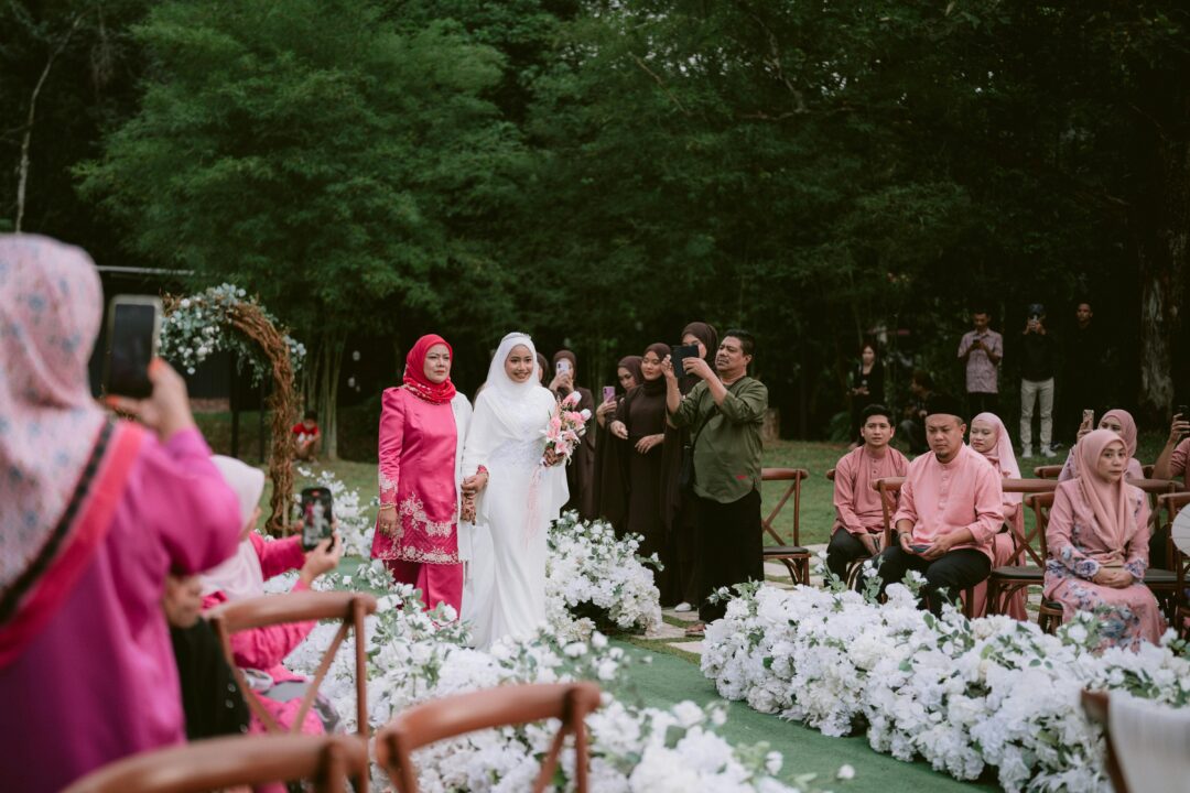bridesmaids walking down a garden ceremony aisle in coordinated pastel dresses, confetti in the air, guests clapping