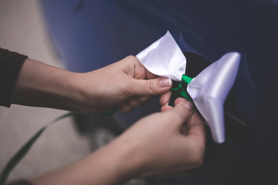 close-up of a florist’s hands tying a silk ribbon around a peony and garden rose bridal bouquet