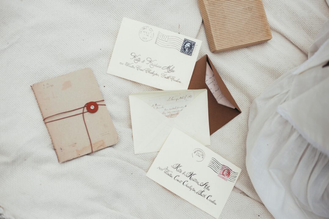 Calligraphy hand addressing a Christmas card envelope on a wooden desk, ink pen close-up with festive minimal styling and natural daylight