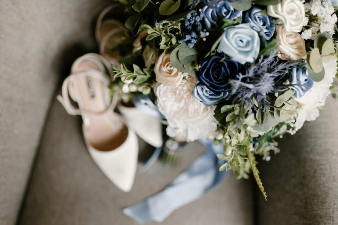 Loose bridal bouquet in dusty blue and blush, hydrangea, garden roses, dusty miller foliage, and ranunculus in a natural, unstructured gather