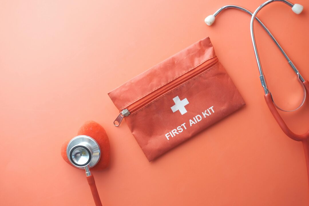 close-up of a wedding planner's organized day-of emergency kit laid out on a white surface, including a mini sewing kit, stain pen, safety pins, and a