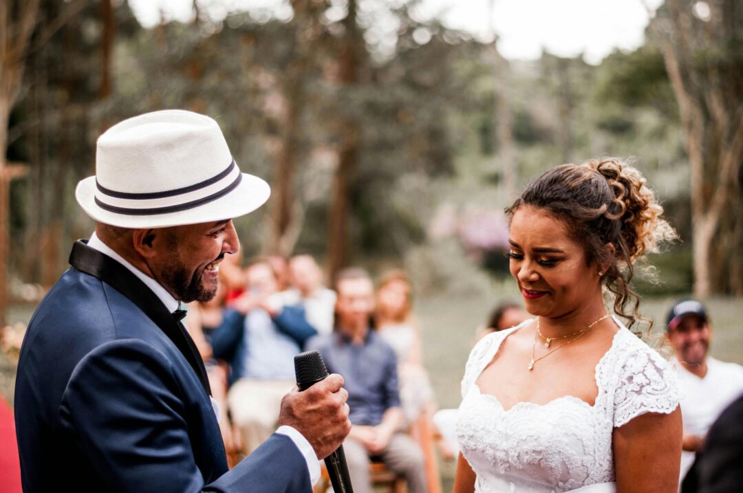 wedding videographer setting up a lapel microphone on a groom before a ceremony in an outdoor garden setting, close-up detail shot