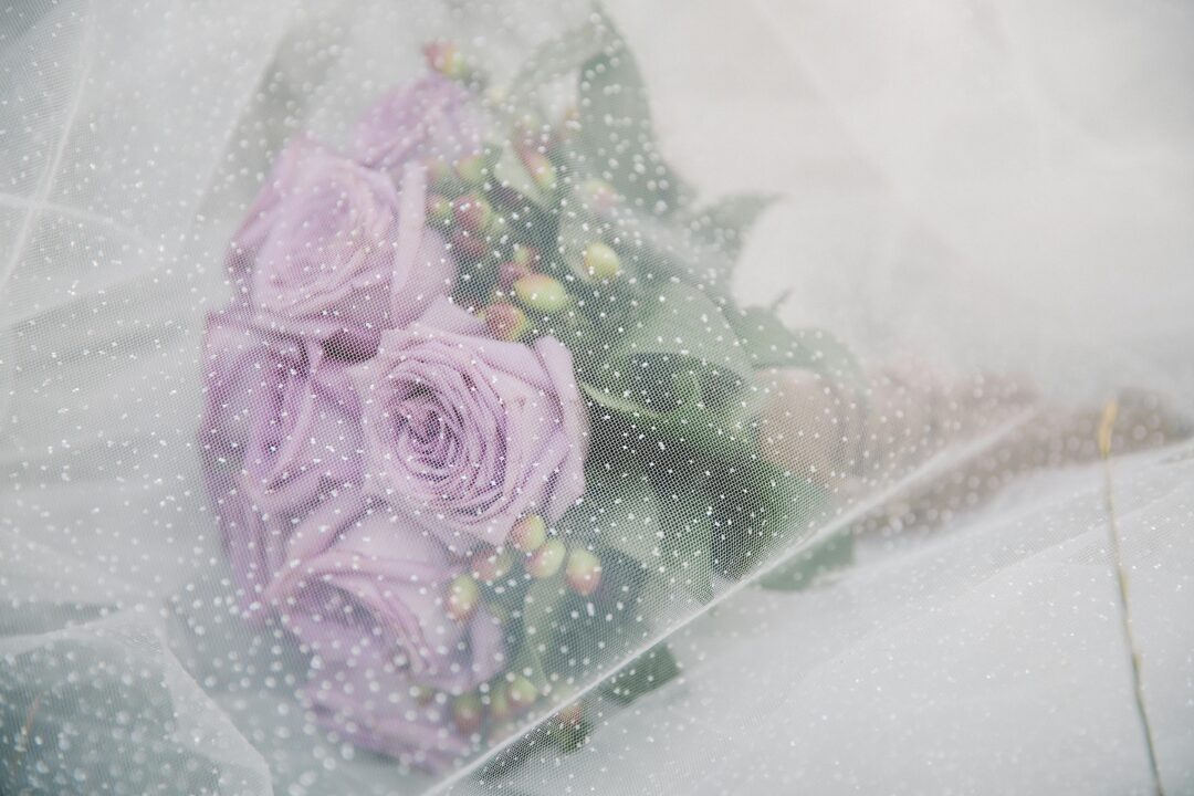 Lavender bridal bouquet with real lavender, scabiosa, blush sweet peas, white garden roses, dusty miller foliage, and lilac wisteria in a soft, loose 