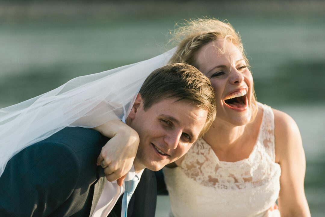 couple sitting together outdoors after their ceremony, relaxed and laughing, ceremony program visible on the grass beside them, candid and natural atm