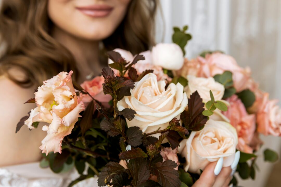 Burgundy and blush bridal bouquet with Black Baccara roses, blush peonies, dusty rose ranunculus, eucalyptus, and dried botanicals in a lush romantic