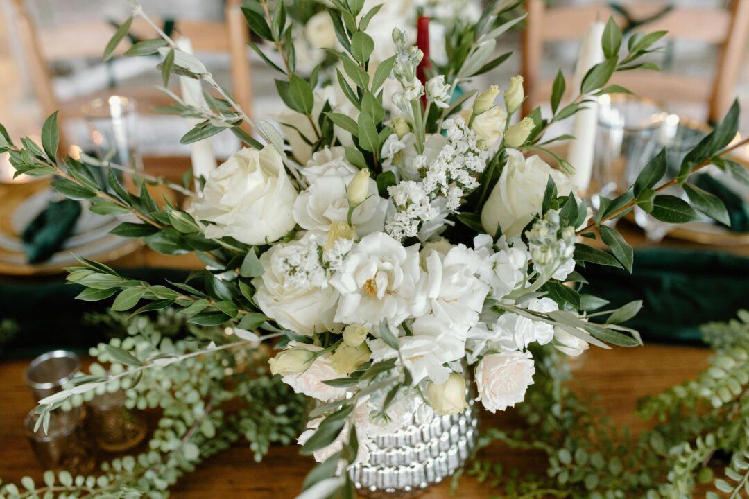 White and charcoal modern wedding centerpiece with white garden roses, white anemone, thistle, and dark foliage in a geometric black vessel on a white