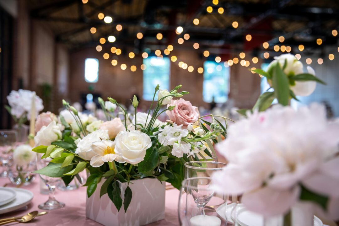 wedding reception centerpiece arrangement of dusty pink and blush peonies in a low geometric gold vessel on a styled table