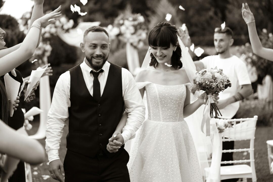 wedding party walking joyfully down a confetti-strewn aisle after the ceremony, bridal party smiling, petals on the ground