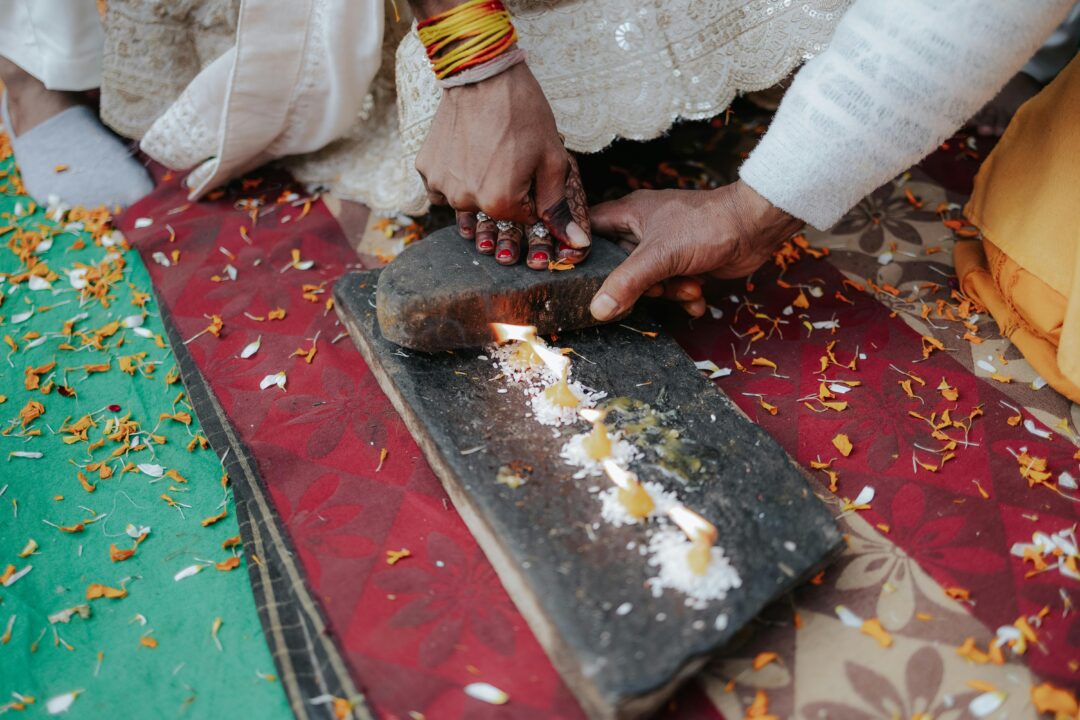 Hindu wedding ceremony with couple performing Saptapadi around a decorated fire ceremony setup, marigold and rose garlands, traditional attire, warm g