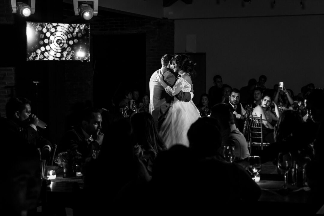 two parents slow dancing with their child-of-honor at a reception, intimate moment, string lights overhead