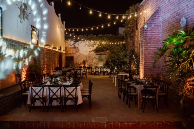 Elegant intimate wedding reception setup with a long wooden table styled with linen napkins, tapered candles, and soft floral arrangements,