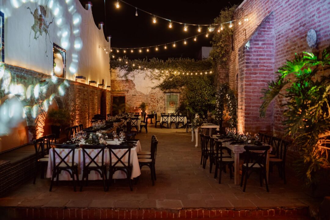 Elegant intimate wedding reception setup with a long wooden table styled with linen napkins, tapered candles, and soft floral arrangements,