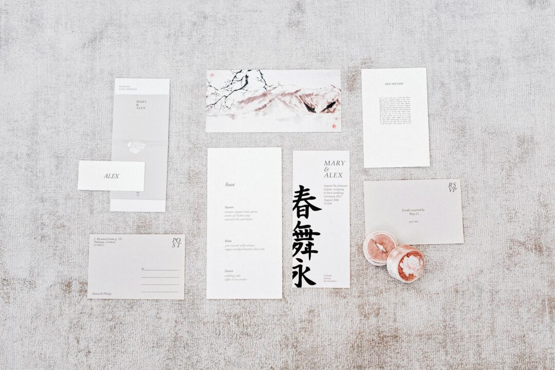 Flat lay of an intimate wedding stationery suite showing a single-sheet letterpress invitation on thick cream cotton paper with gold foil sc