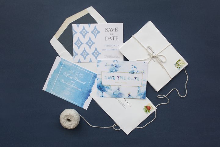 Flatlay of multiple Paperlust save the date card designs in navy blue with watercolour botanical accents