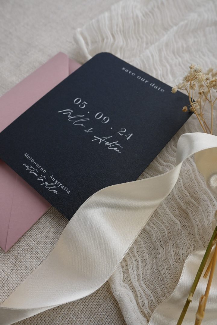 Paperlust dark navy save the date card with white typography on linen textile paired with blush florals