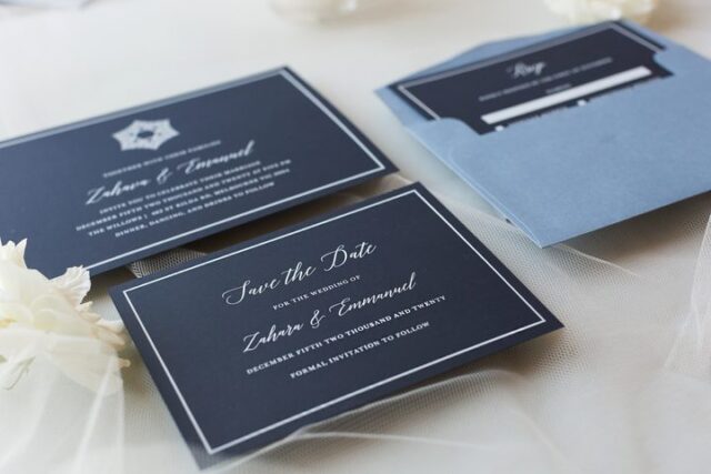 Paperlust navy save the date card flatlay with white typography and matching envelope for Zahara and Emmanuel