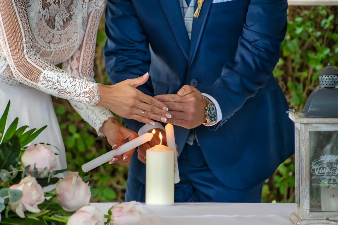 candle unity ceremony moment, bride and groom lighting central candle from individual flames