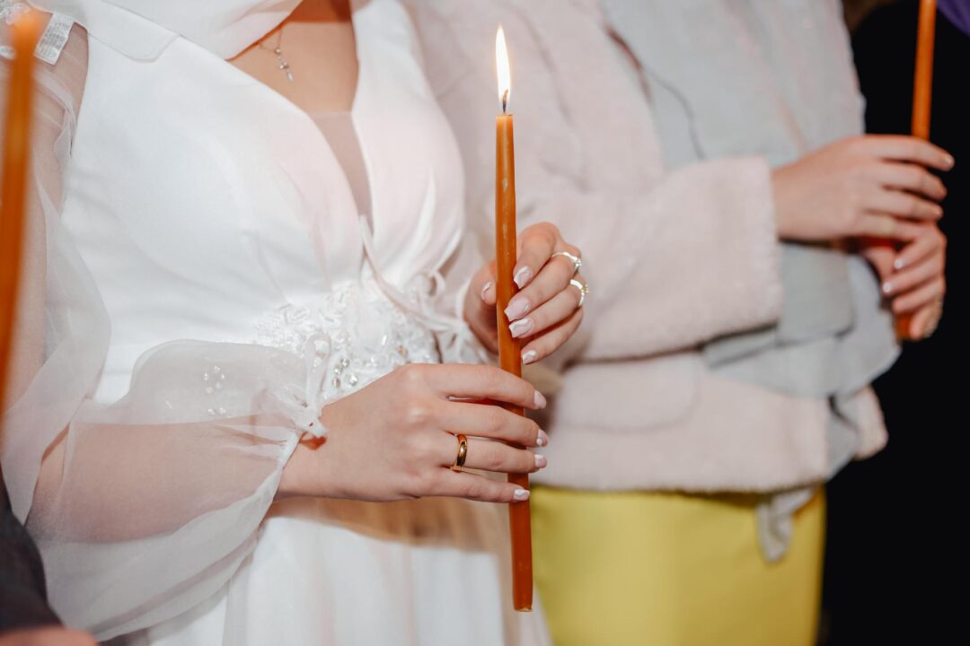 Close-up of a bride holding a lit candle during a wedding ceremony, symbolizing unity and love.