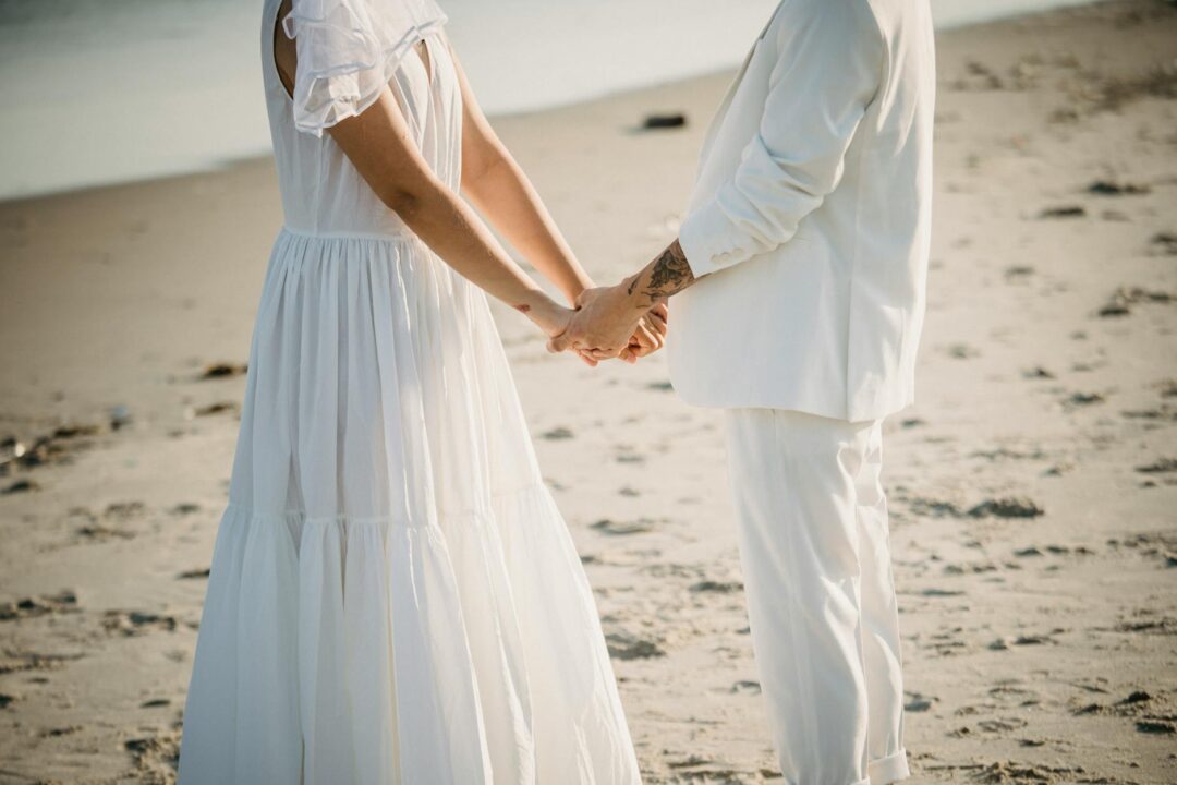 sand ceremony at a beach wedding, two partners pouring colored sand into a glass vase