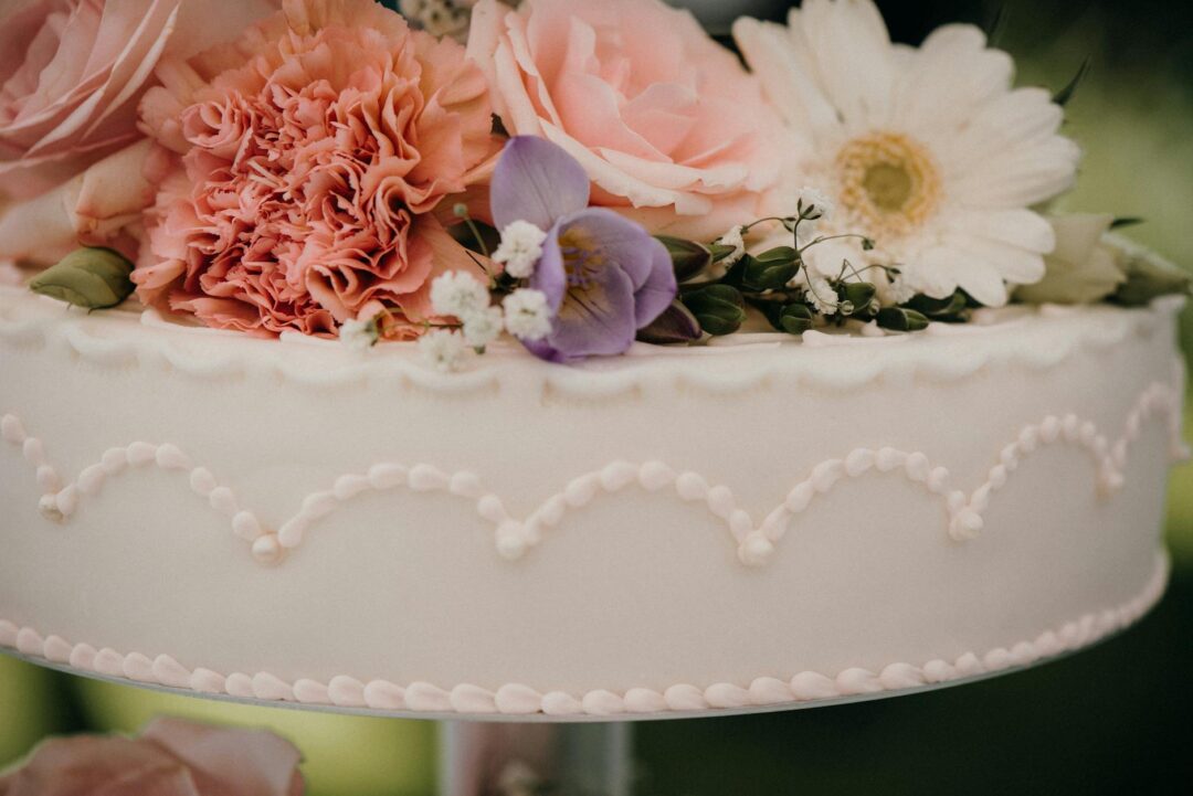 close-up of ornate Lambeth-style buttercream piping on a wedding cake, ivory scrollwork swags and shells in tone-on-tone, elegant and sculpt