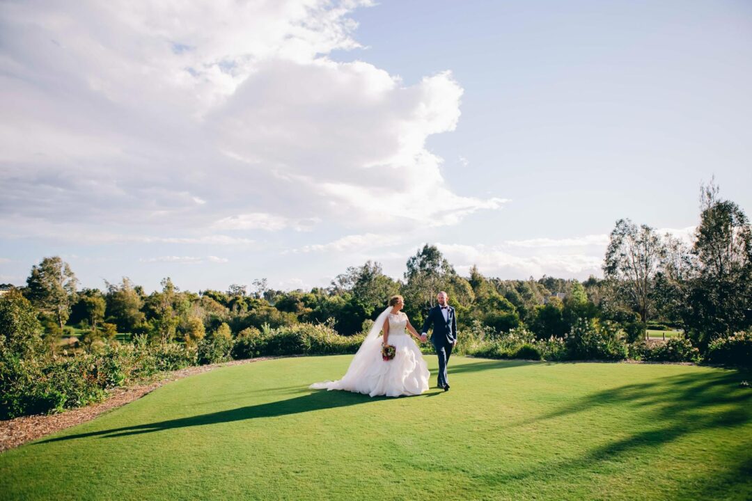 outdoor Australian wedding cocktail hour, guests mingling on a sun-drenched lawn while waitstaff pass elegant trays of canapés, warm golden