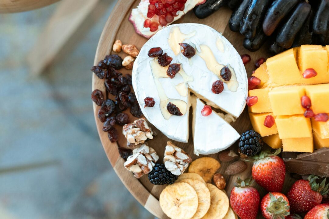 elegant wedding grazing table with Australian cheeses, antipasto, fresh seasonal fruit, edible flowers, and artisan crackers arranged on tim