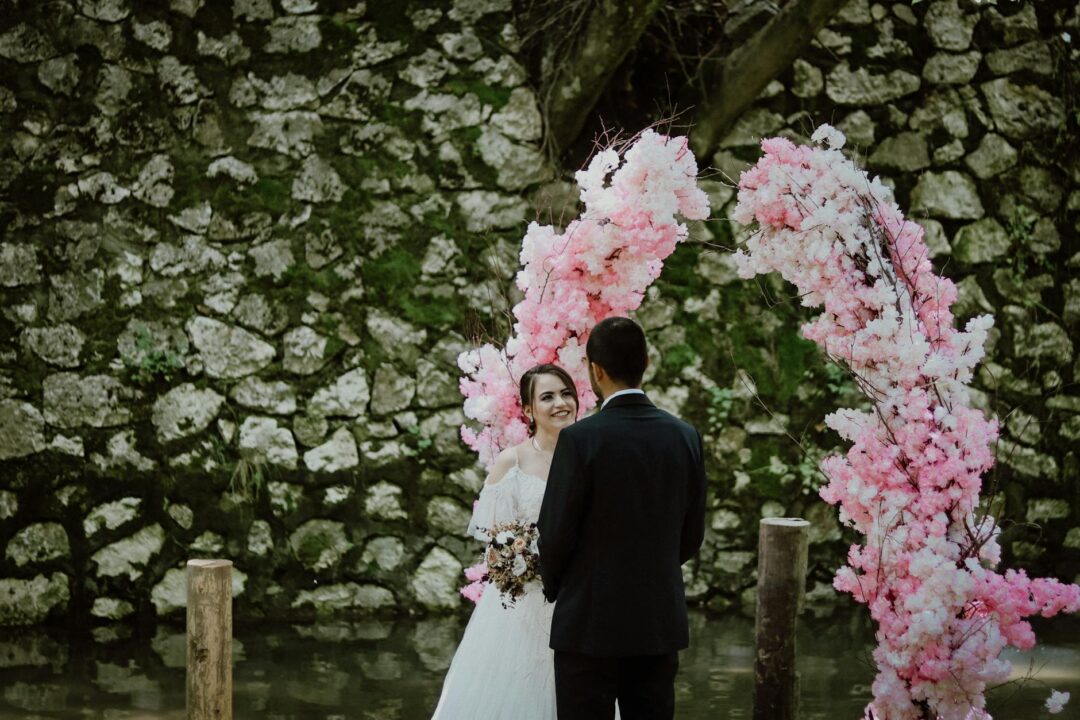 romantic outdoor wedding ceremony with floral arch, white chairs lining a petal-strewn aisle, warm natural light
