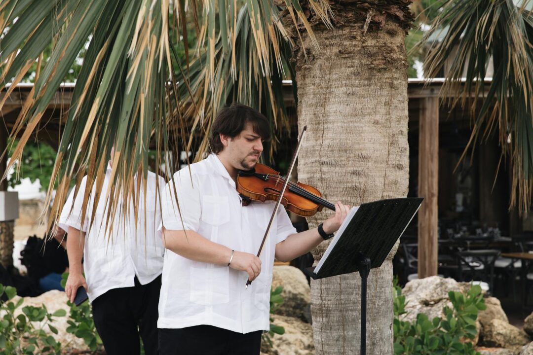 string quartet performing at outdoor garden wedding ceremony, guests seated on white chairs