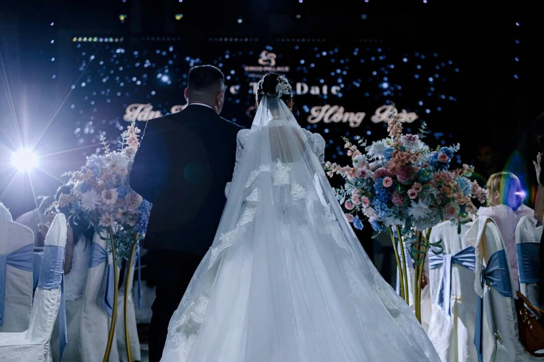 bride walking down the aisle with natural light from large windows, guests standing