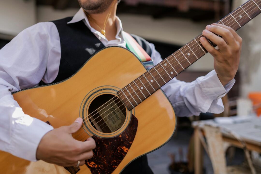 acoustic guitarist playing for guests at outdoor ceremony cocktail hour transition, warm afternoon light