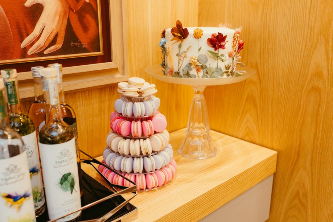 styled wedding dessert table with macarons, mini cupcakes, a donut wall, white florals, and gold accents arranged on tiered cake stands and