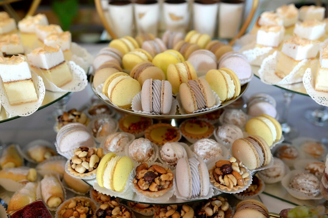 A lavish display of colorful macarons and assorted pastries on a tiered dessert platter.