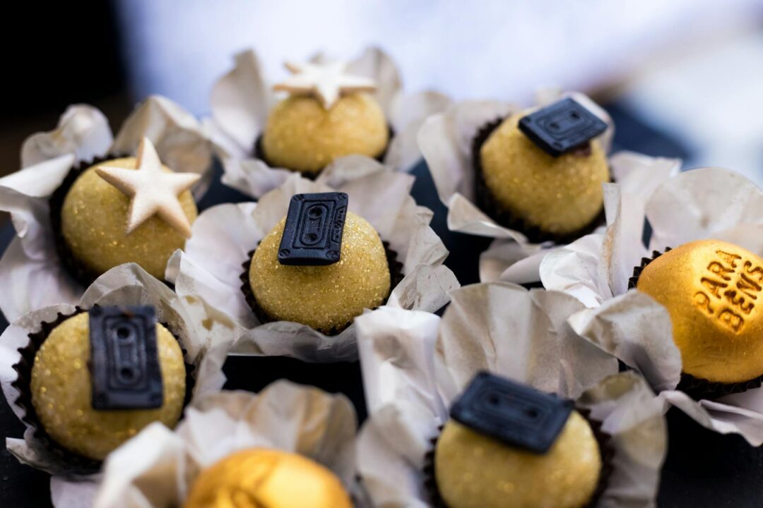 overhead flatlay of edible wedding favors including mini honey jars, small cookie bags, and individually wrapped chocolates, each tagged wit