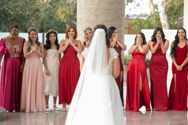 emotional first look moment, groom's back, bride approaching in white gown, soft natural light filtering through trees