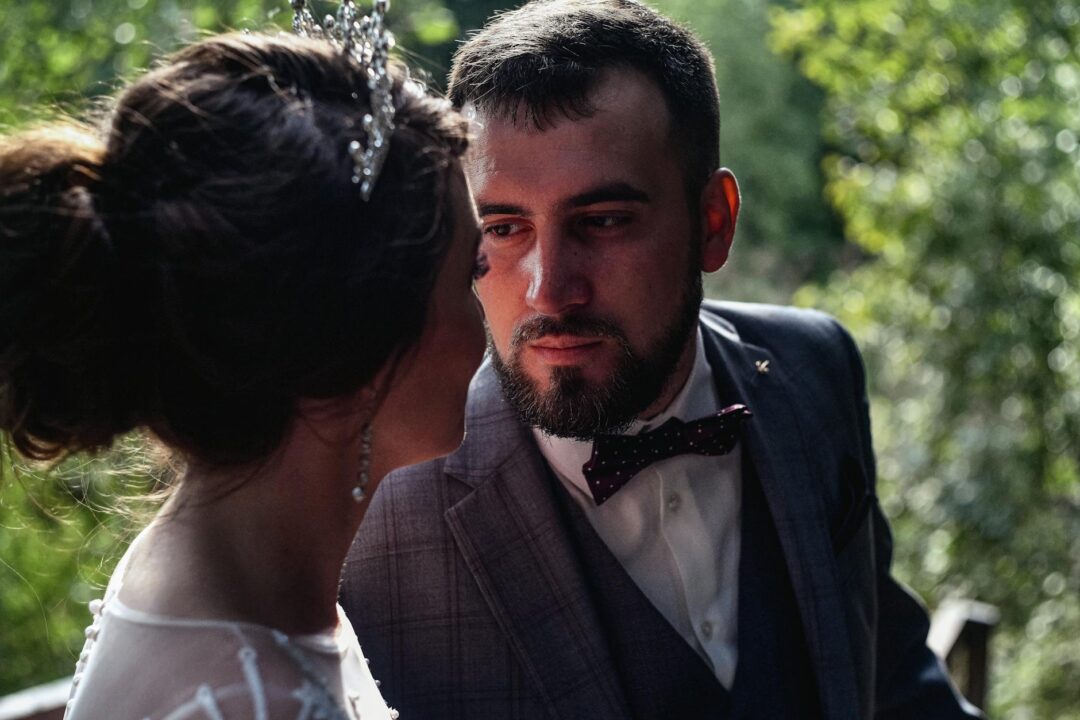 close-up of groom's face as he turns to see bride for first time, expression showing overwhelmed emotion, natural light setting