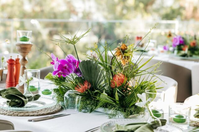 Elegantly styled wedding reception table with floral centerpiece and plated first course, warm evening lighting