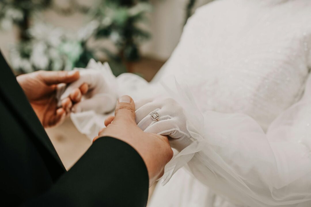 Couple's hands holding elegant white wedding thank you cards with gold flat foil monogram lettering on a marble surface, Paperlust design fl