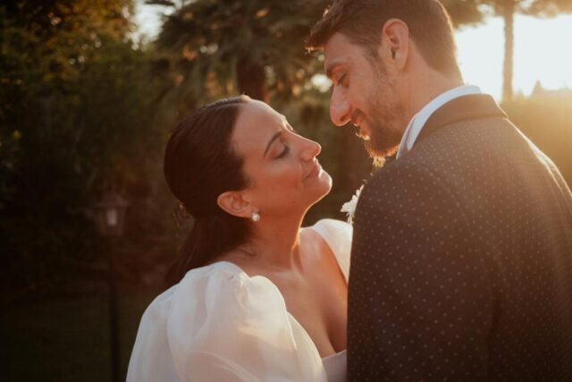 Wedding couple portraits at golden hour, soft backlit glow, bride in flowing dress, outdoor venue setting