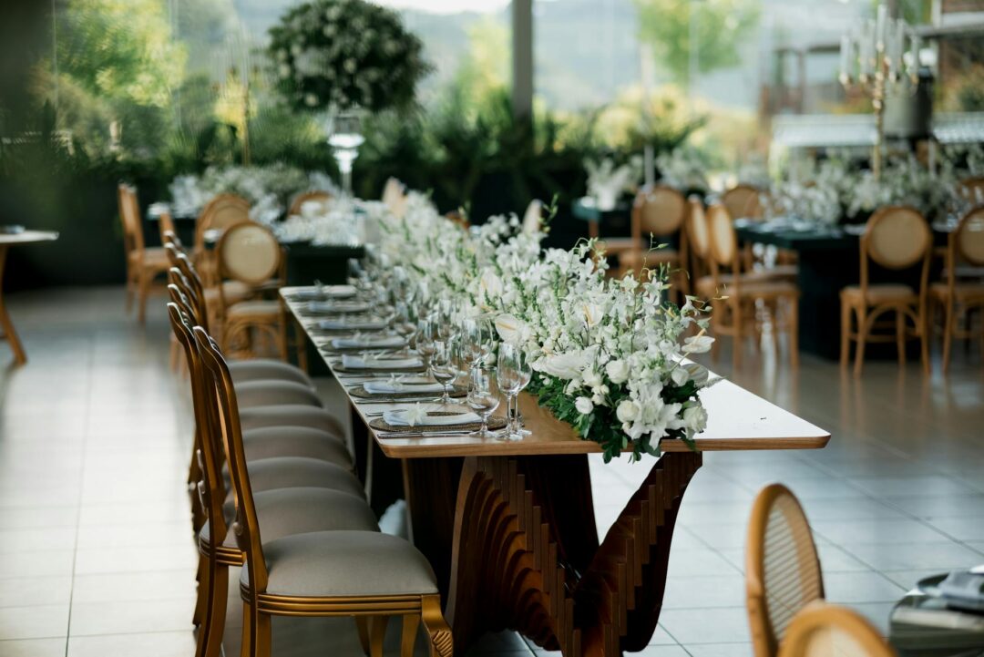 Wedding reception table setup with centerpiece flowers, candles, place cards, and folded menus, soft warm evening light
