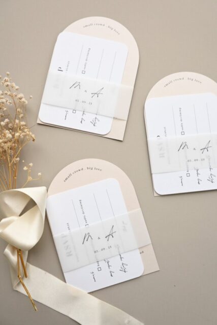Paperlust wedding invitation suite flat lay with arch cards, RSVP cards, dried florals, and satin ribbon detail styling
