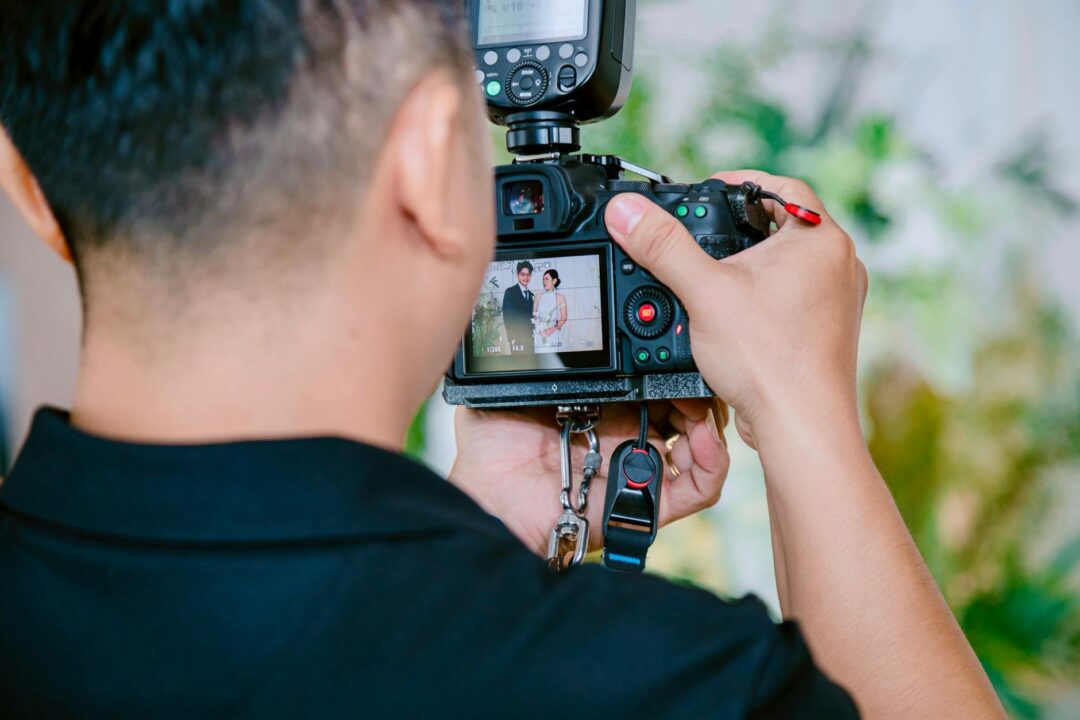 A photographer focuses on capturing a wedding couple using a digital camera during a ceremony.