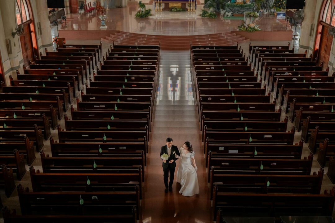 bride and groom walking away from ceremony venue, editorial candid shot with guests visible in background