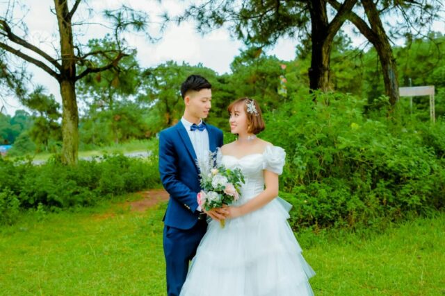 Bride and groom posing together outdoors at a wedding venue, holding hands and laughing naturally in soft golden-hour light